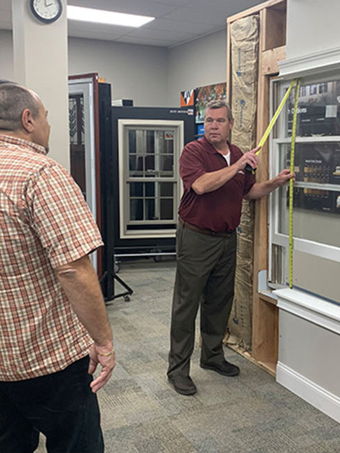 WindowRama employee showing off a double hung window ins a showroom