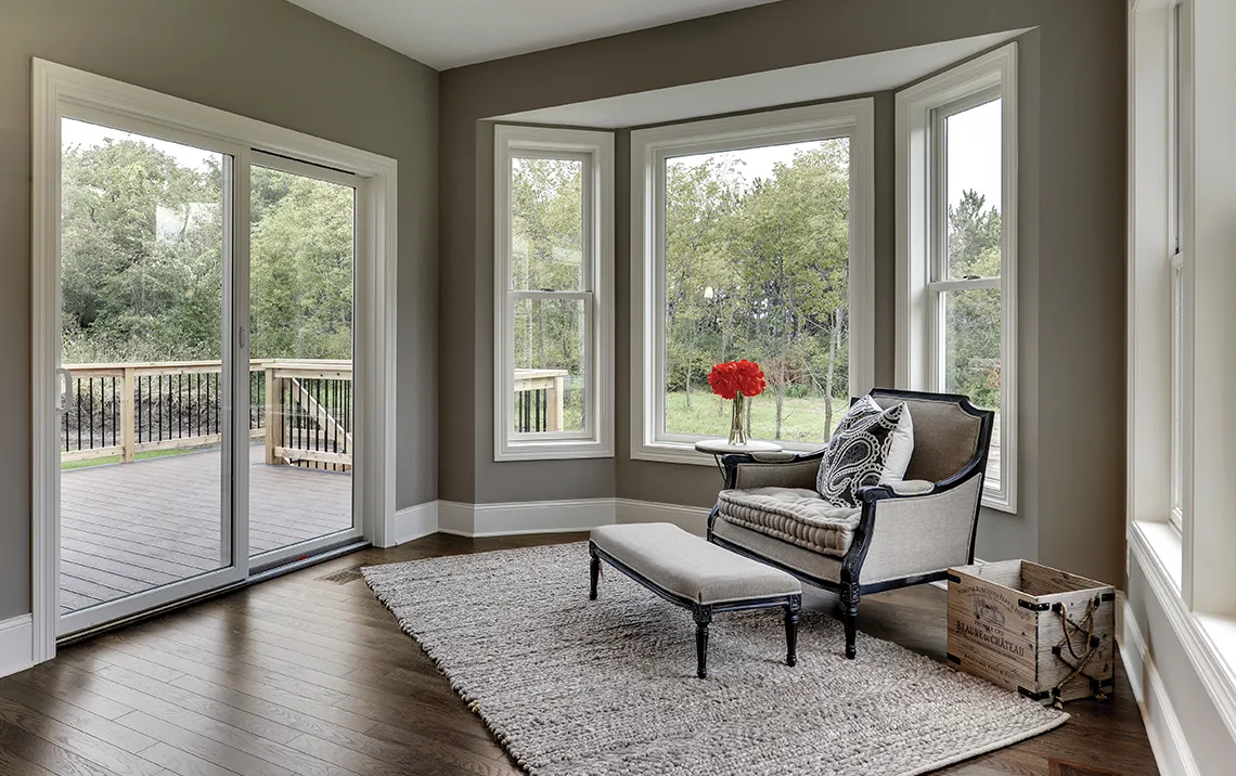 back door leading to a wooden deck with wood floors and a single chair with an ottoman