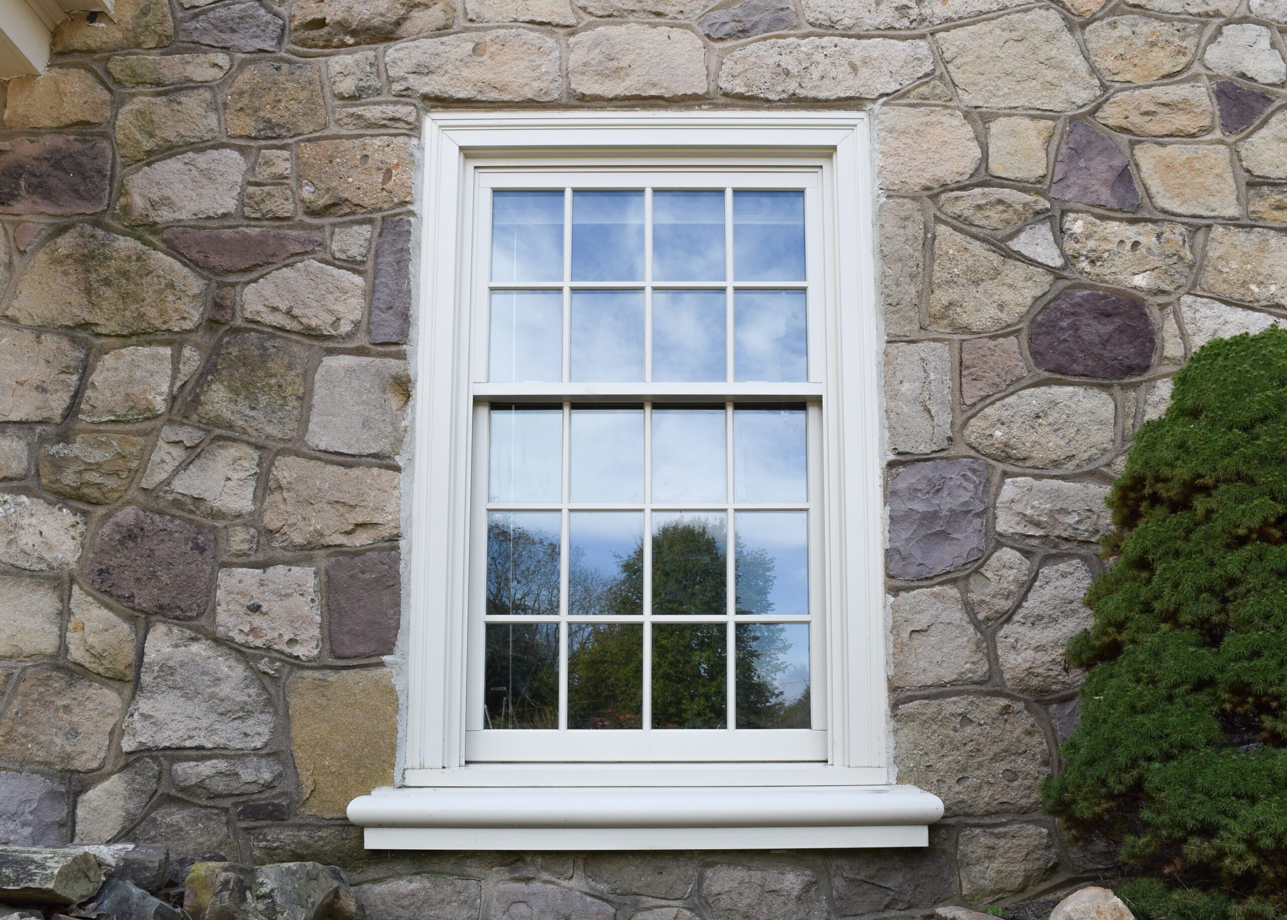 single double hung window outside with a stone wall