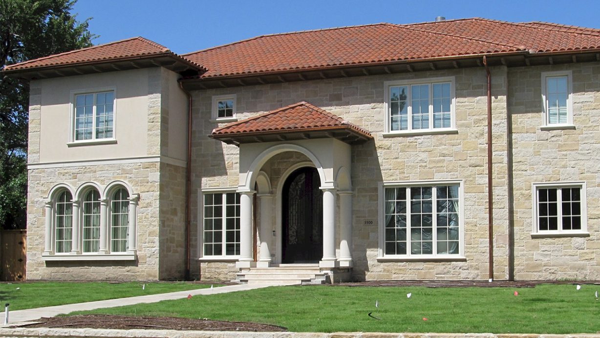 a large two story tan brick house with arched entrance door