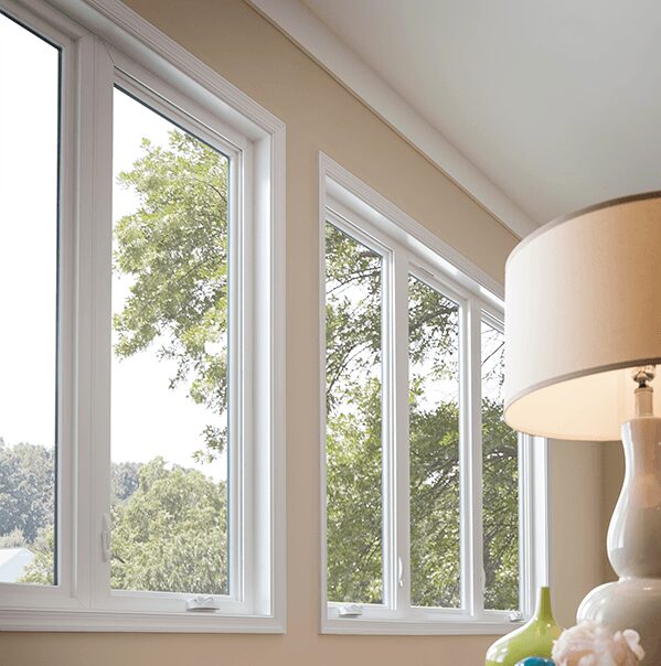 a table lamp in front of casement windows against a peach colored wall