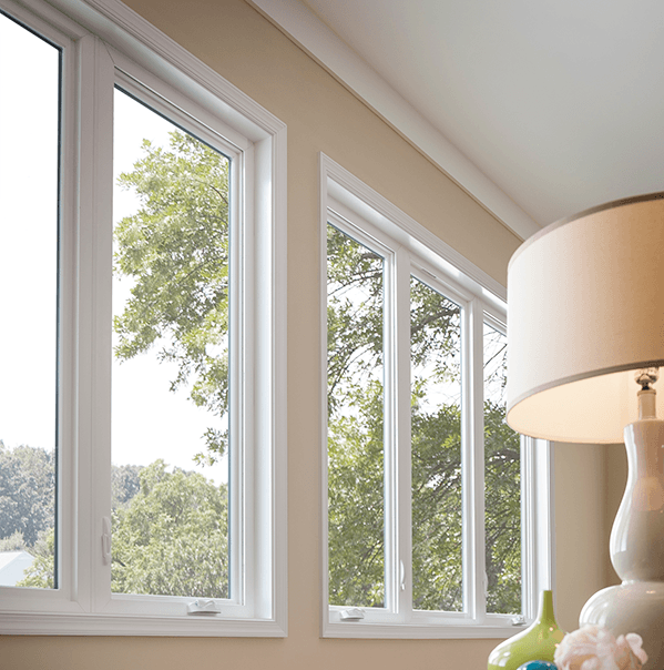 a table lamp in front of casement windows against a peach colored wall