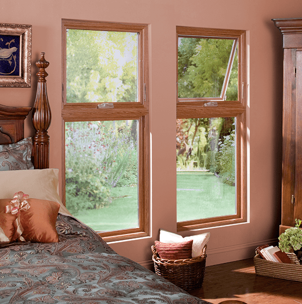 Awning windows in a cozy pink colored bedroom with a bed on a wooden bedframe