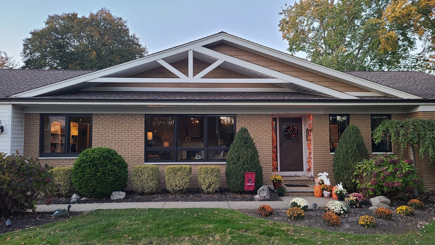 front entrance of a brick home exterior with fall decorations and black framed windows