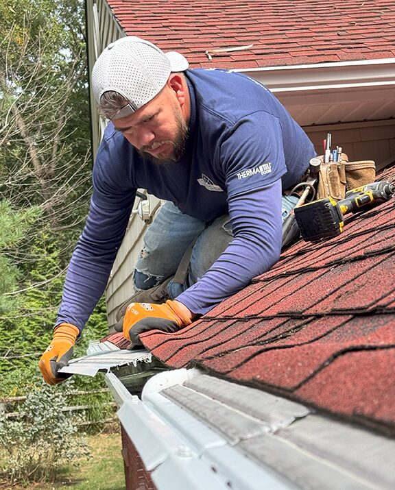WindowRama installer fitting MasterShield gutter protection along a roof edge